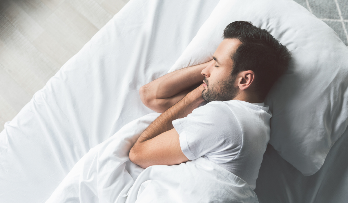 Man Sleeping On Side In Bed With White Bedding